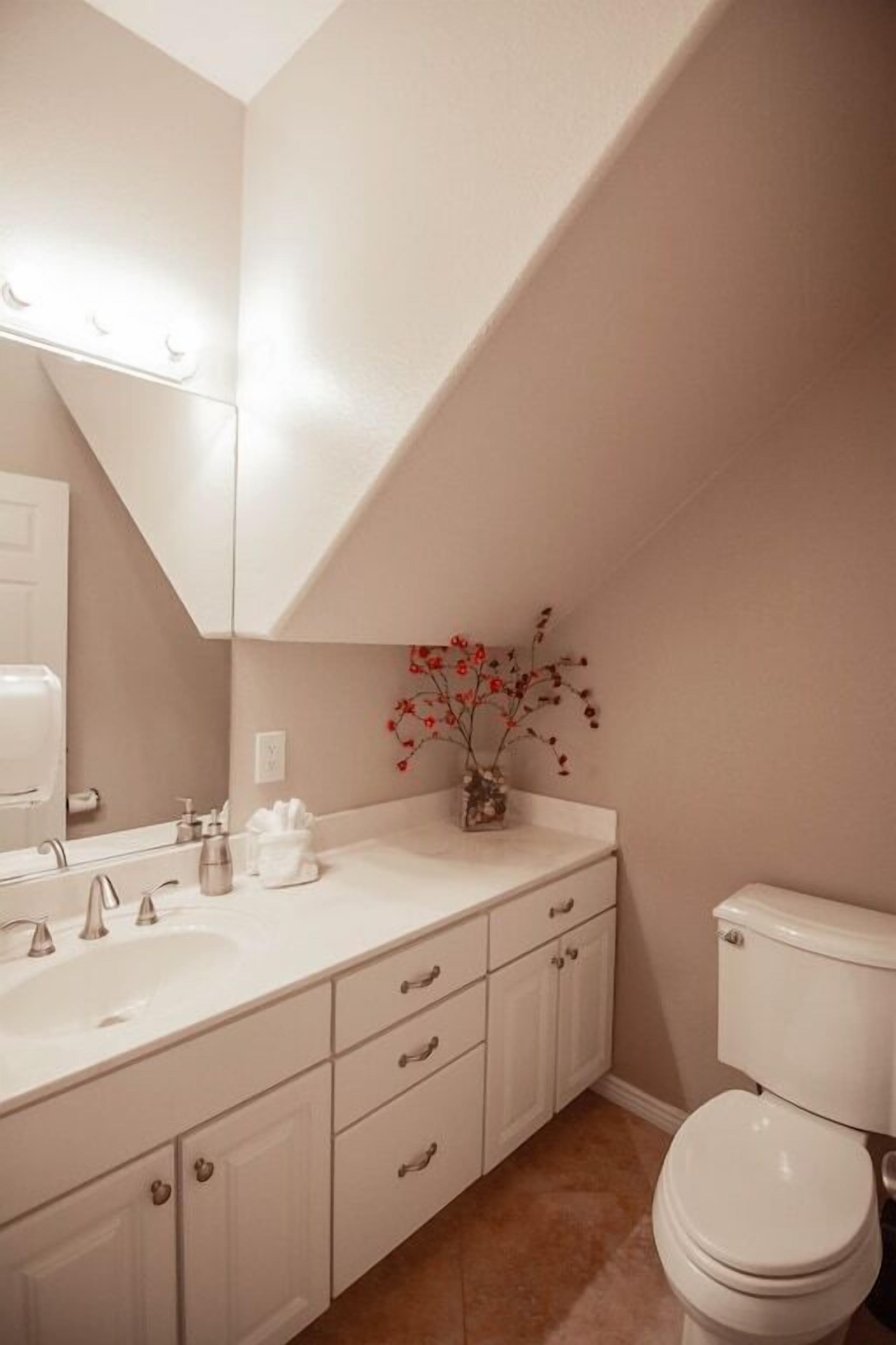 A modern bathroom with a white vanity, a toilet, and a mirror.