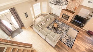 A spacious living room with a large sectional sofa, a patterned rug, a fireplace, and a ceiling fan. - Spacious Retreat with 2 Master Suites, Foosball & AC (Flagstaff)