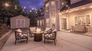 A patio with outdoor seating and a fire pit, surrounded by string lights. - Spacious Retreat with 2 Master Suites, Foosball & AC (Flagstaff)