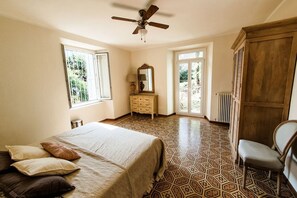 Un dormitorio con cama, cómoda, silla y ventana.
