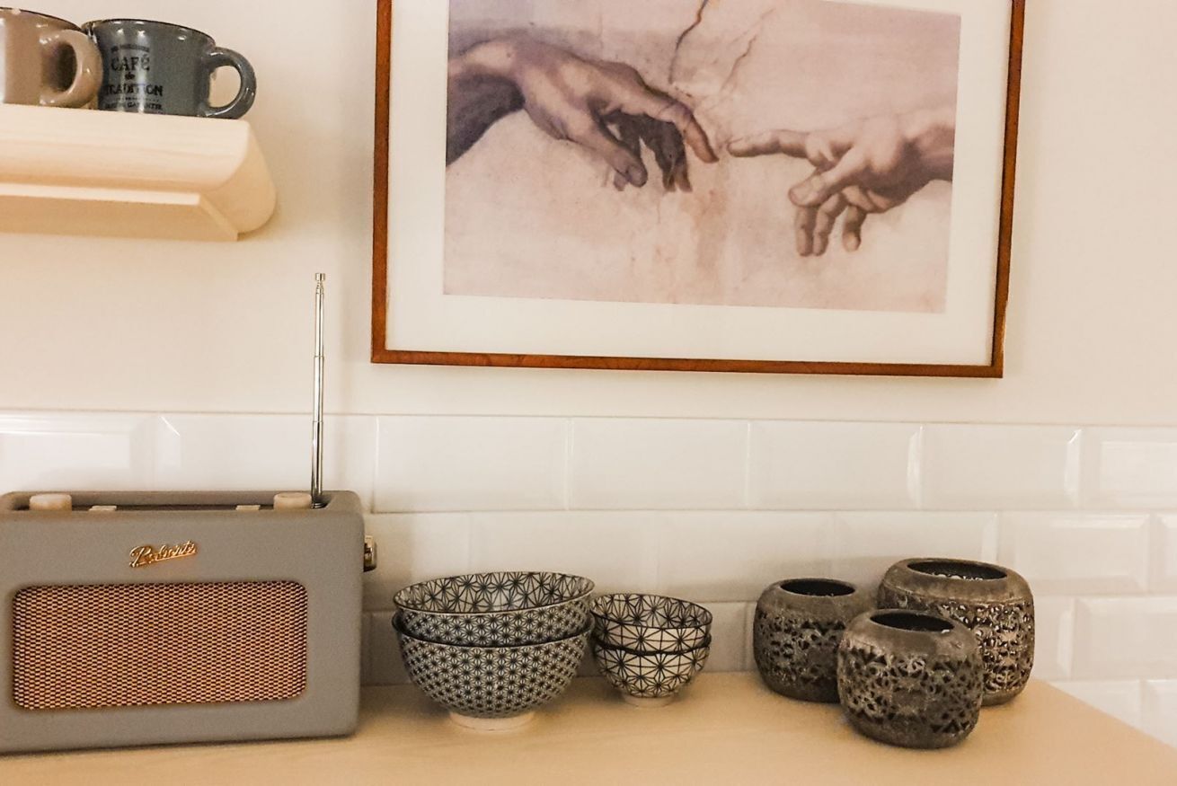 A kitchen with a radio, patterned bowls, and a framed artwork.
