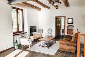 A living room with a wooden coffee table, a sofa, a chair, and a television.
