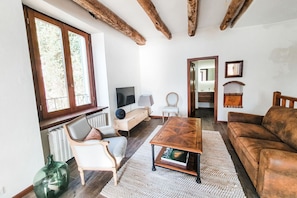 A cozy living room with a wooden coffee table, a brown leather sofa, a white armchair, and a television.