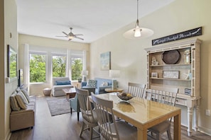 A spacious living area with a dining table, sofas, and a bookshelf.