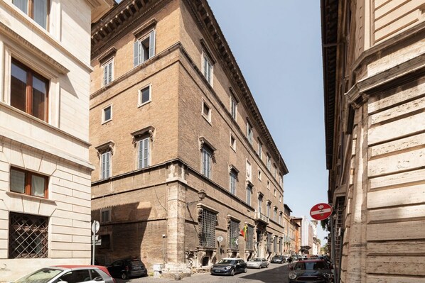 A narrow street lined with historic buildings, featuring a mix of brick and stone facades, and a no-entry sign visible on the right.
