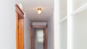 Un couloir étroit avec un plancher en bois et des murs blancs.