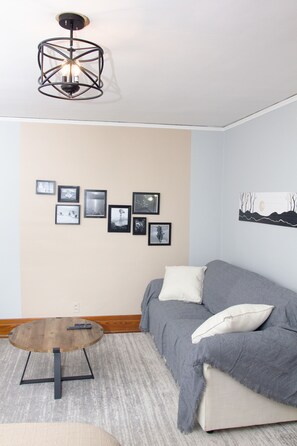 A living room with a grey sofa, a wooden coffee table, and a wall-mounted light fixture.