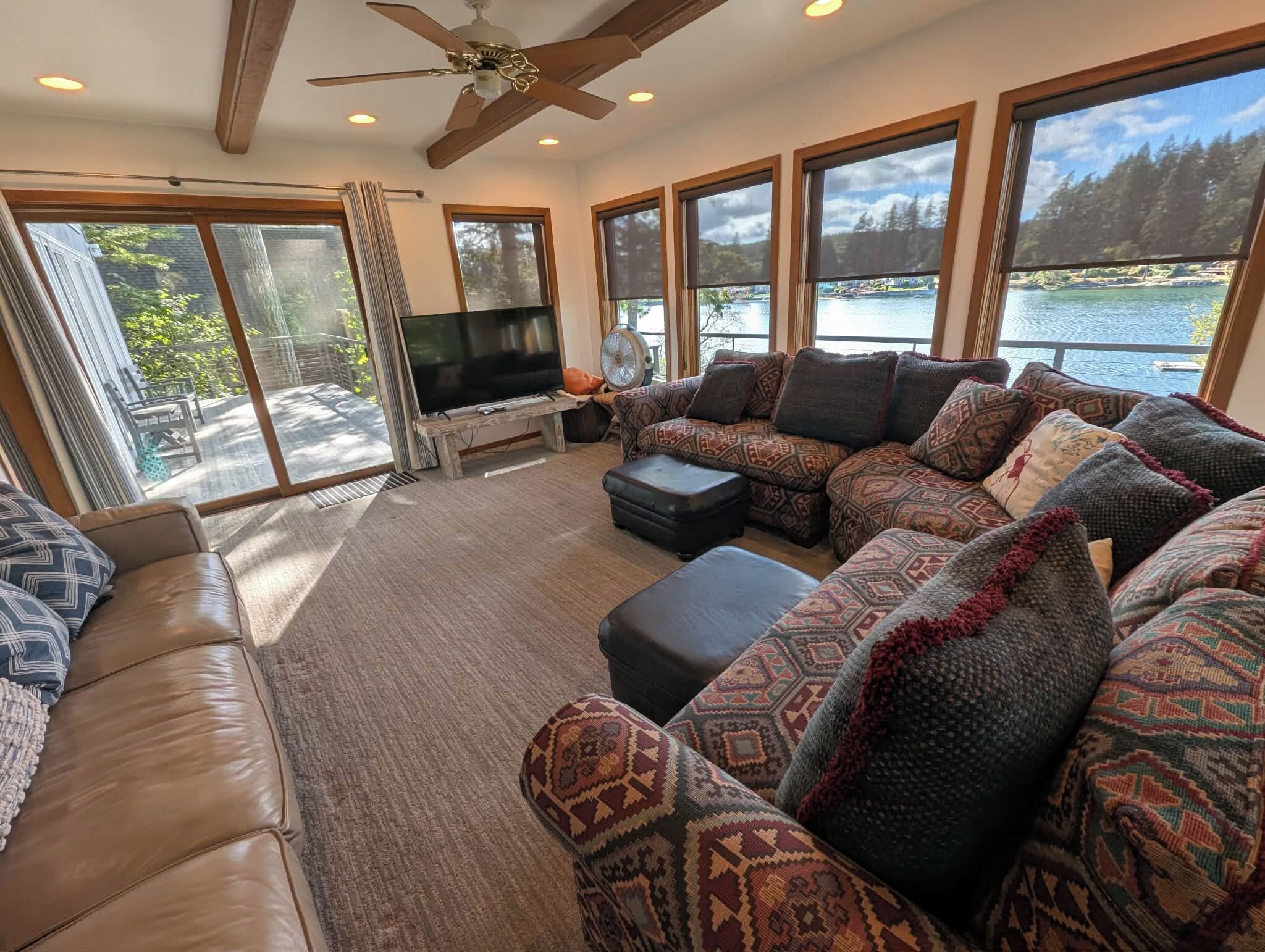 A spacious living room with a large sectional sofa, a flat-screen TV, and a ceiling fan.