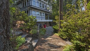 Uma casa moderna de dois andares rodeada por uma floresta densa.