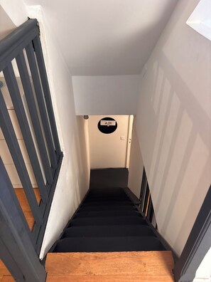 A narrow staircase with wooden steps and a black handrail, leading to a landing with a circular warning sign. - The Leaning House with a Private Jacuzzi (Rosny-sous-Bois)