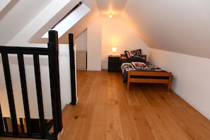 A bedroom with a sloped ceiling, a bed with a patterned bedspread, a nightstand, and a lamp. - The leaning house with private Jacuzzi (Rosny-sous-Bois)