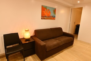 A living room with a brown sofa, a black chair, and a table with a lit lamp. - The leaning house with private Jacuzzi (Rosny-sous-Bois)