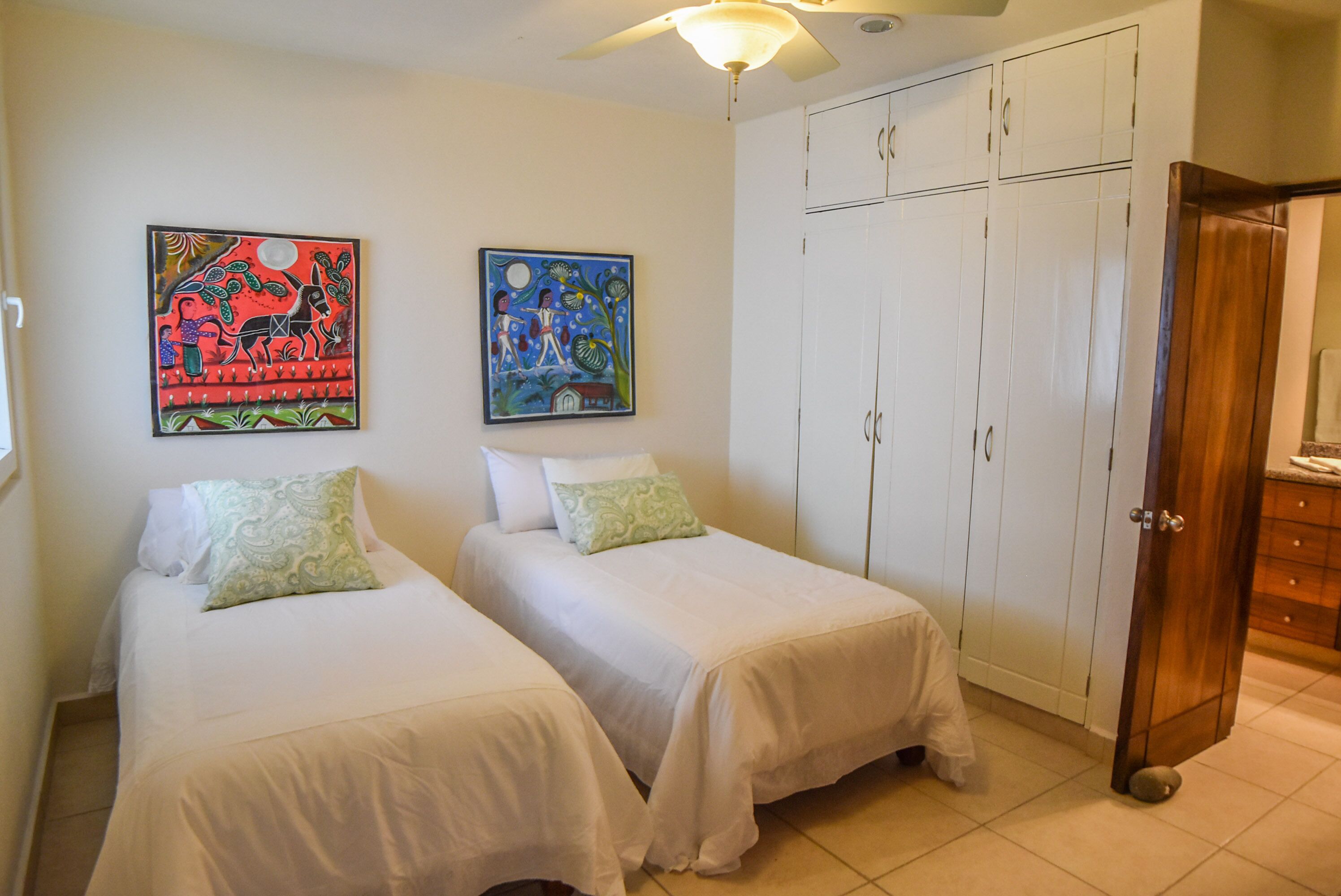 A bedroom with two single beds, a wardrobe, and two wall art pieces.
