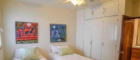 A bedroom with two single beds, a wardrobe, and two wall art pieces.