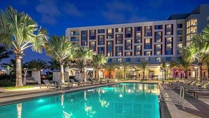 Un hôtel doté d’une piscine, de palmiers et d’une façade de bâtiment moderne.