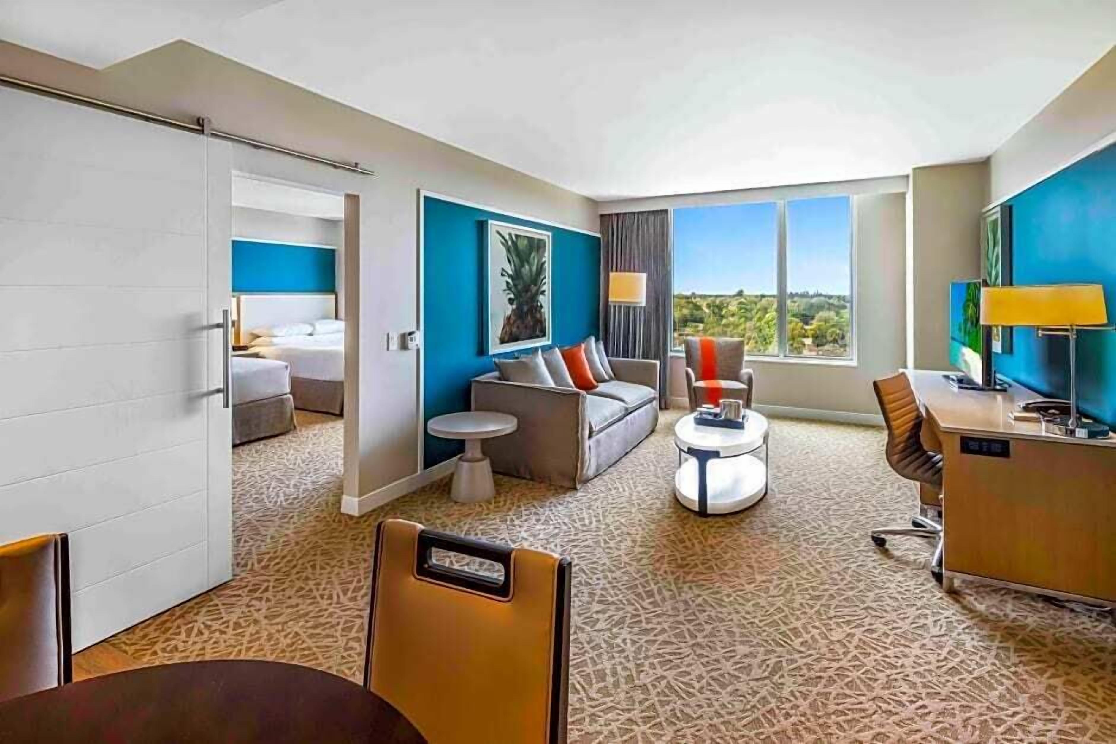 Una habitación de hotel con cama, sofá, escritorio y vistas al exterior.