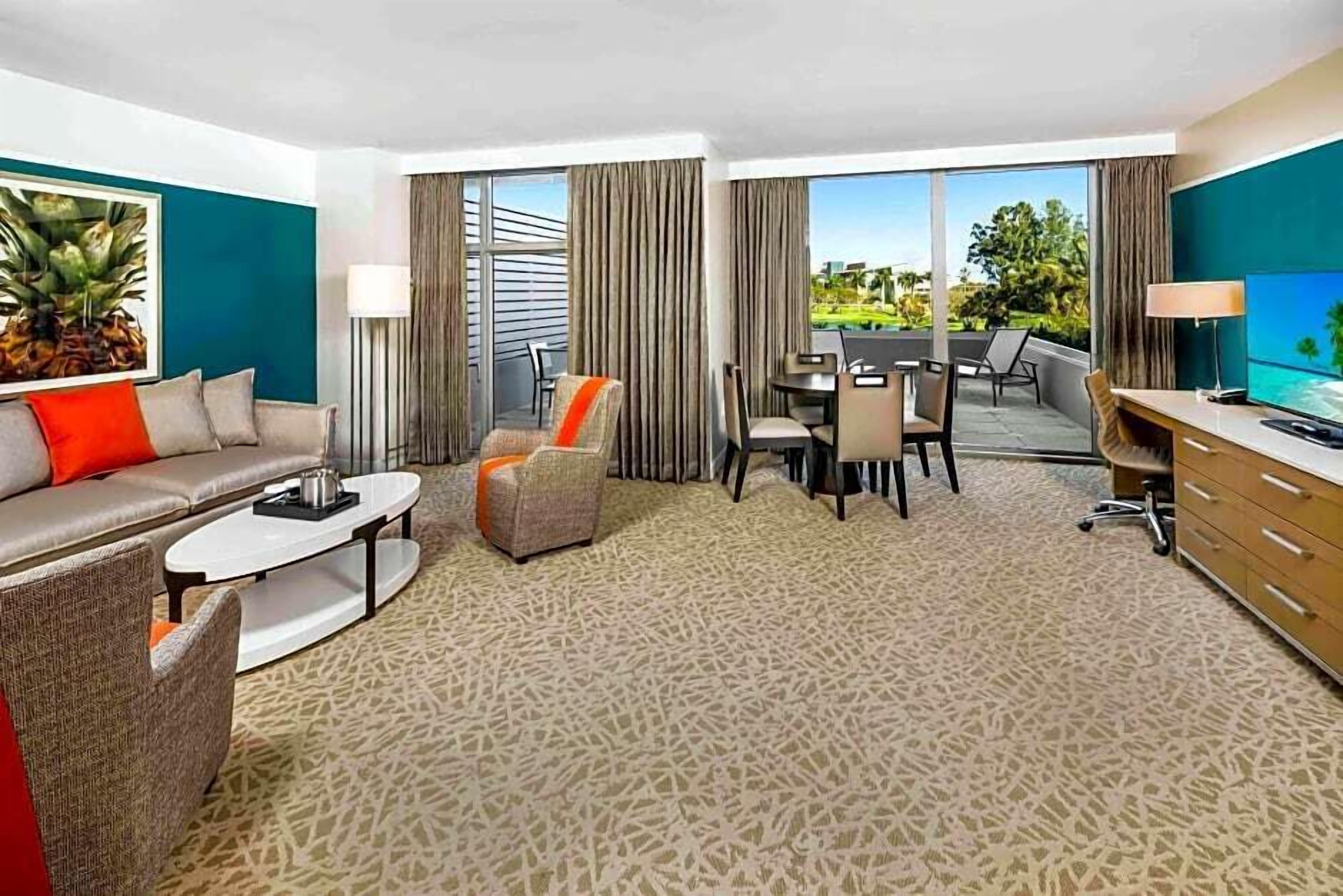 Una habitación de hotel con sala de estar, una mesa de comedor y televisión.