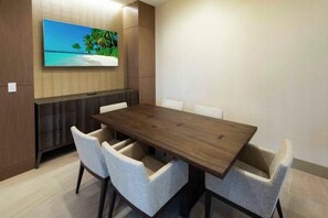 A conference room with a long table, four chairs, a flat-screen TV mounted on the wall, and a wooden cabinet. - Hilton Miami Dadeland (Miami)