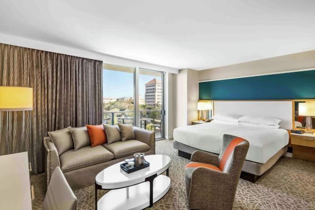 Ein Hotelzimmer mit Bett, Sofa, Sessel, Couchtisch und Blick auf die Stadt.