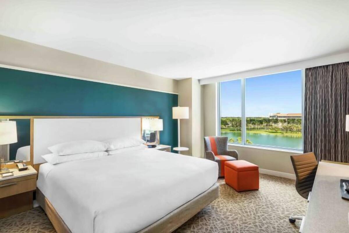 Ein Hotelzimmer mit einem großen Bett, einem Schreibtisch, einem Sessel und Blick auf einen Golfplatz.