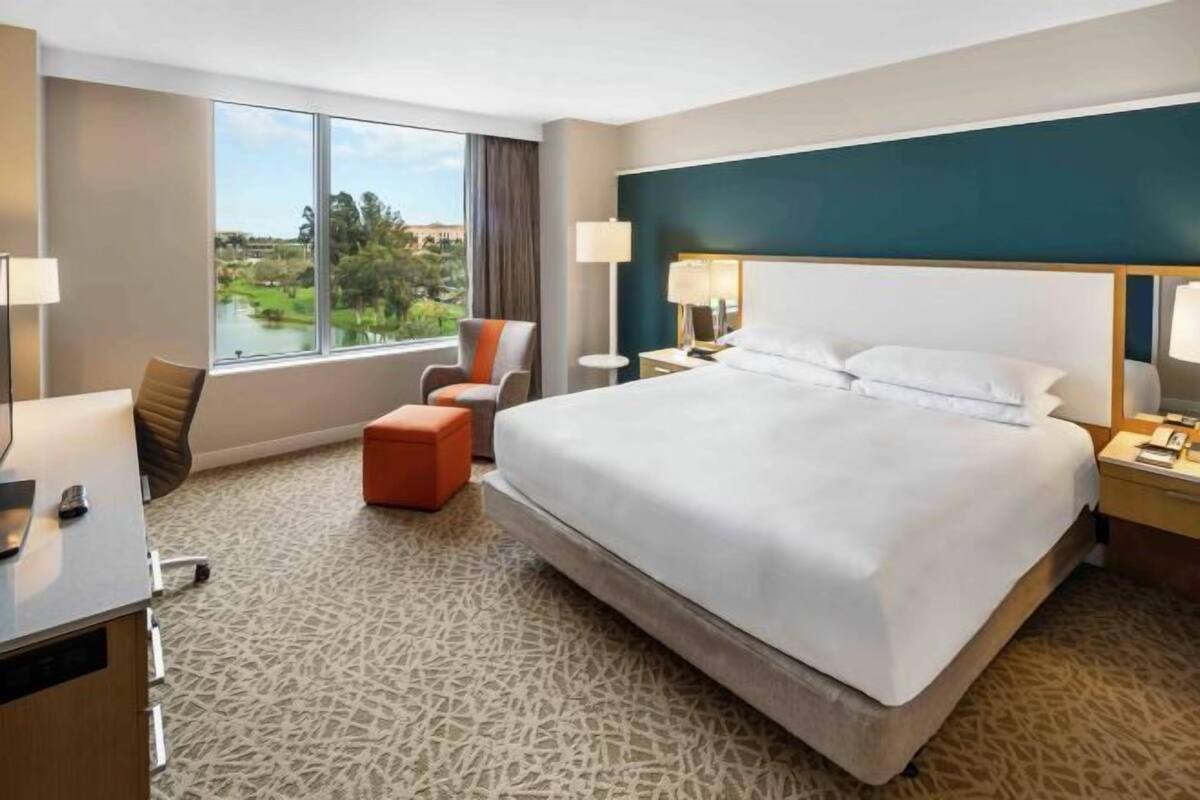 Ein Hotelzimmer mit einem großen Bett, einem Schreibtisch, einem Stuhl und Blick auf einen See.