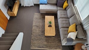 A modern living room with a sofa, a coffee table, and a TV stand. - Relaxing Spot with Stunning Sea View! (Snells Beach)
