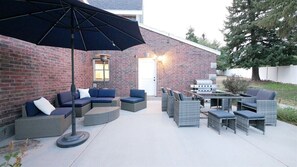 An outdoor patio with wicker furniture, a grill, and a large umbrella. - 6 Bed 6 bath Country Red Brick Home (Eden)