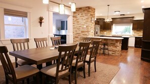 A modern kitchen with a stone accent wall, wooden dining table, and dark cabinetry. - 6 Bed 6 bath Country Red Brick Home (Eden)
