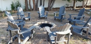 A circular arrangement of Adirondack chairs around a fire pit.