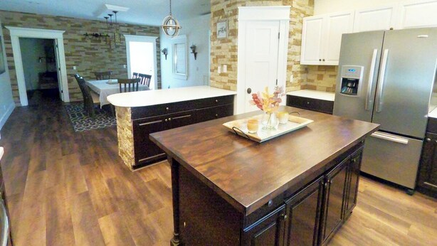 A kitchen with a central island, a refrigerator, and a stone accent wall. - 6 Bed 6 bath Country Red Brick Home (Eden)