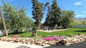 A backyard with a lawn, trees, a wooden deck, and a stone wall. - 6 Bed 6 bath Country Red Brick Home (Eden)