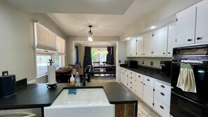 A modern kitchen with white cabinetry, a central island, and a black oven. - Updated in 2021 Notre Dame Football Weekend Entertaining Home (South Bend)