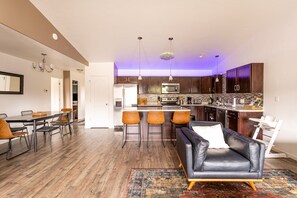 A modern kitchen with a central island, bar stools, and a dining area with a table and chairs. - Contemporary 3 bedroom townhome in downtown Fruita (Fruita)