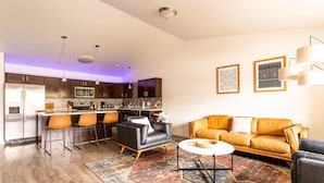 A modern kitchen with a central island, bar stools, a sofa, and a coffee table.