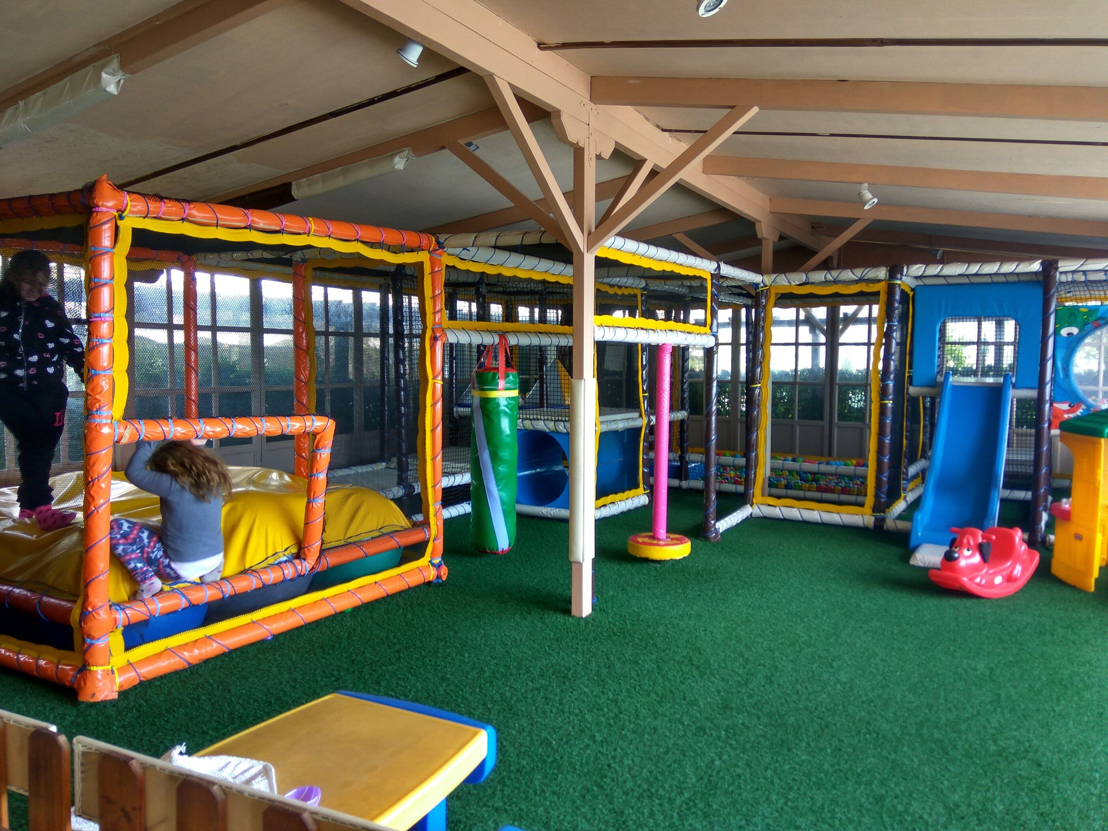An indoor play area with padded play structures, a ball pit, and a slide.