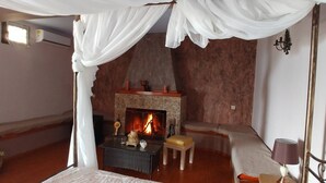 A cozy room with a fireplace, a small table with a candle, and a bench. - Villa in Malaki in Sea With PlayGround (Malaki)