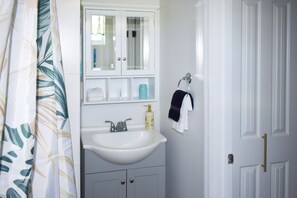 Un baño con un lavabo blanco, un espejo y un armario.