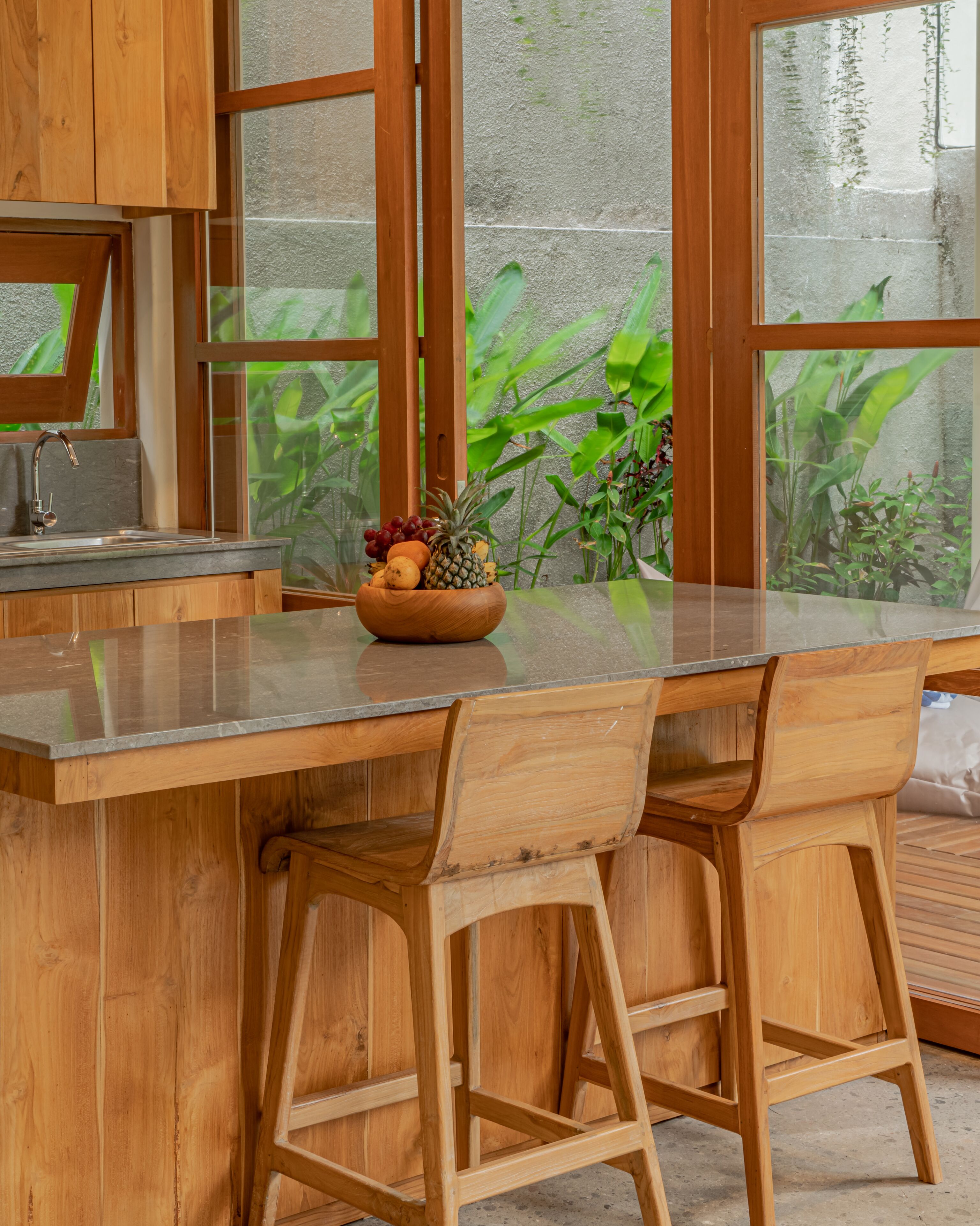Una cocina con armarios de madera, encimera de granito y un bol de fruta en la isla.