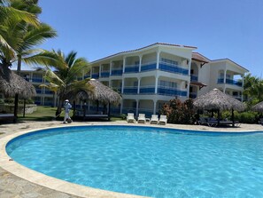 Un resort con piscina, palme e un edificio con balconi.