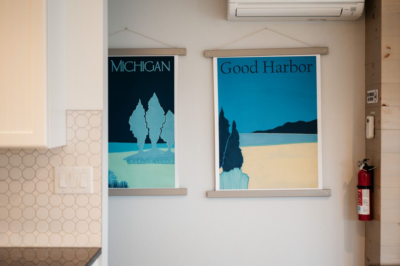 Deux affiches encadrées sont accrochées au mur, l’une portant l’inscription « Michigan » et l’autre « Good Harbor ». Un extincteur est fixé au mur, à droite.