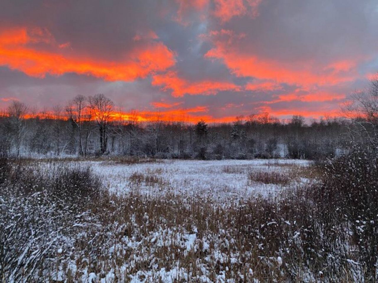 Un champ enneigé sous un ciel au coucher du soleil.