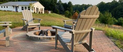 Un patio con sillas Adirondack y una chimenea.