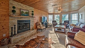 A cozy living room with a fireplace, leather furniture, and a wooden ceiling. - Charming Hamilton Farmhouse w/ Country Views! (Gustine)