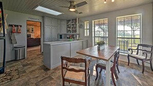 A spacious kitchen with a central island, white cabinetry, and a dining area with wooden chairs. - Charming Hamilton Farmhouse w/ Country Views! (Gustine)