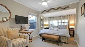 Ein Schlafzimmer mit Bett, Stuhl, Fernseher und Fenster.