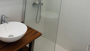 Um banheiro moderno com chuveiro envidraçado, pia branca e espelho.