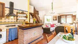Une cuisine avec un îlot central en briques, un lave-linge et un coin repas comprenant une table et des chaises.