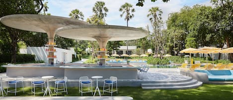 An outdoor pool area with a bar, seating, and umbrellas.