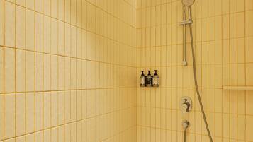 A small, tiled shower room with a handheld showerhead and a wall-mounted faucet.