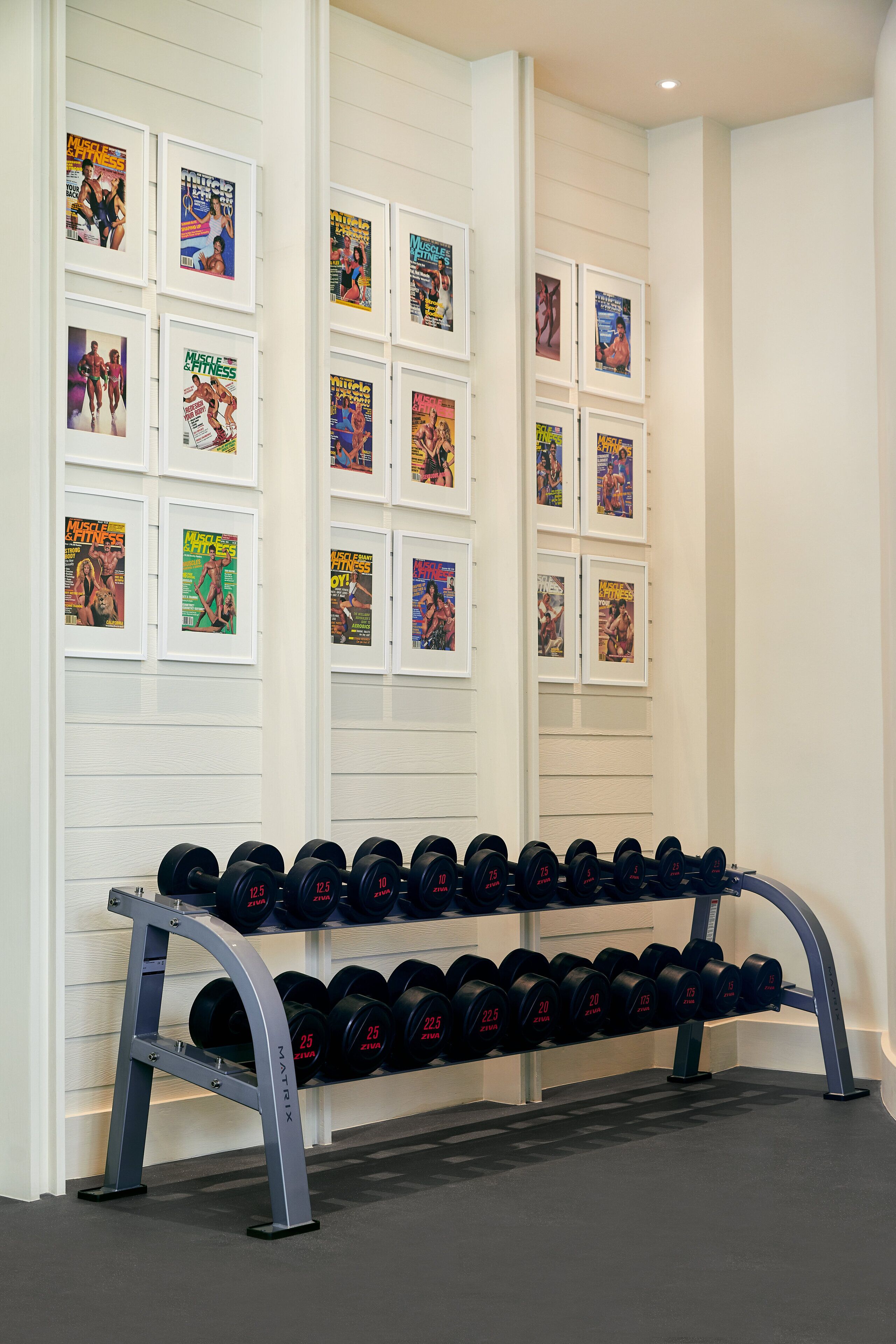 A gym with a wall of framed fitness magazines and a rack of dumbbells.
